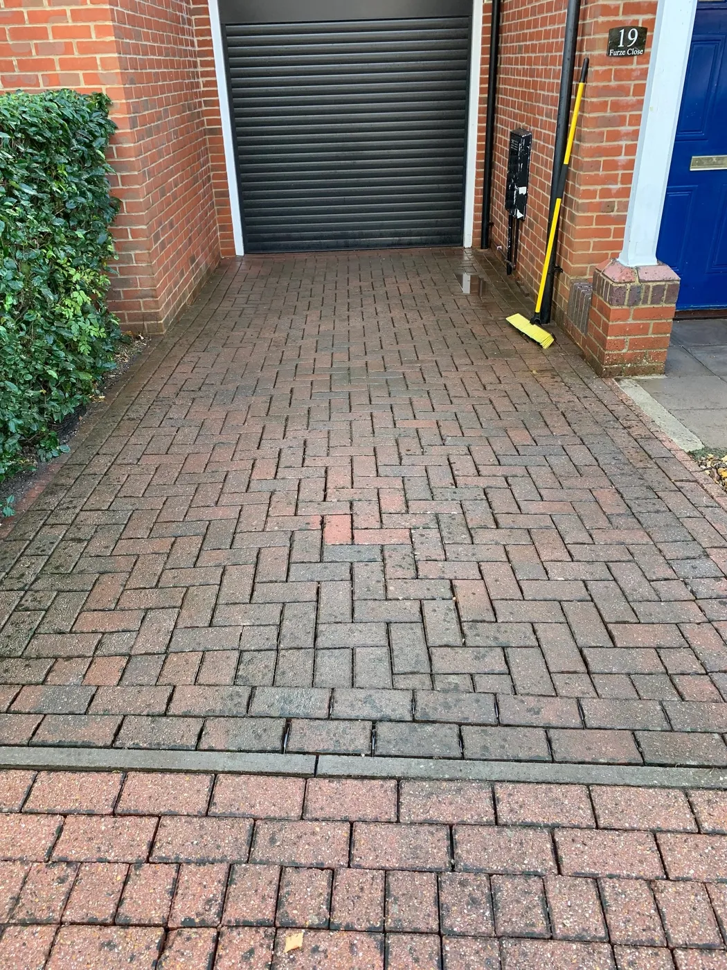 A freshly cleaned block-paving driveway beside a garage