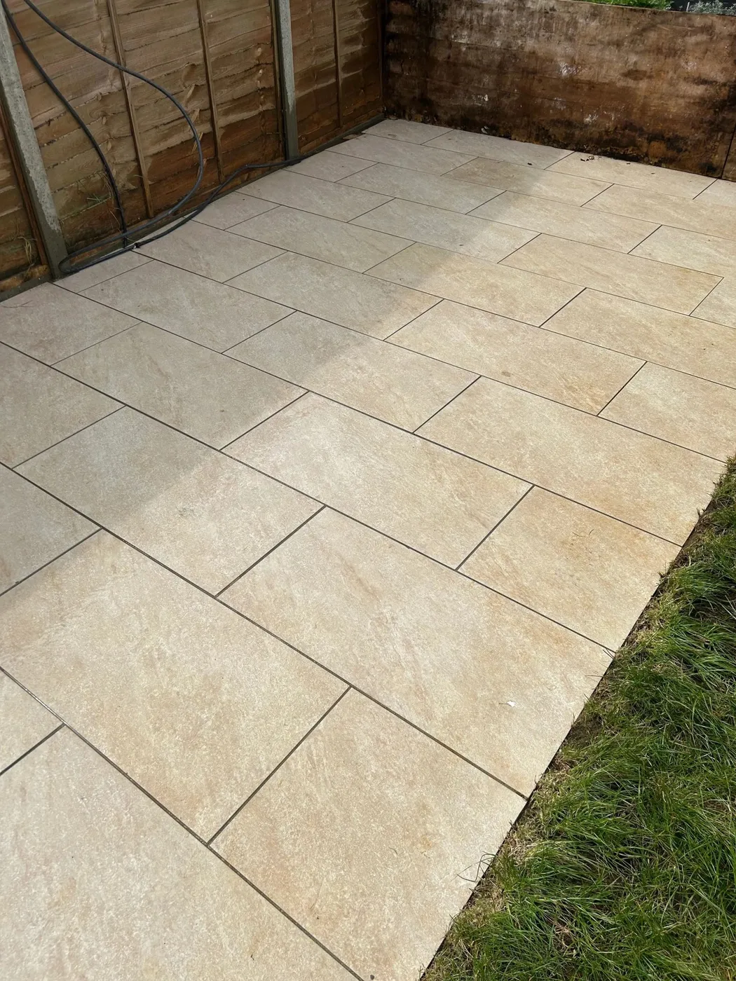 A clean beige porcelain-slab patio in an enclosed garden