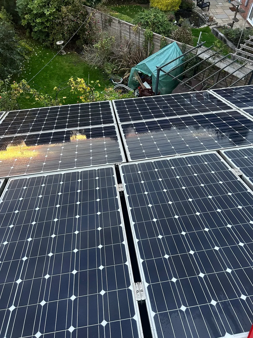 Rooftop solar panels being cleaned above a garden