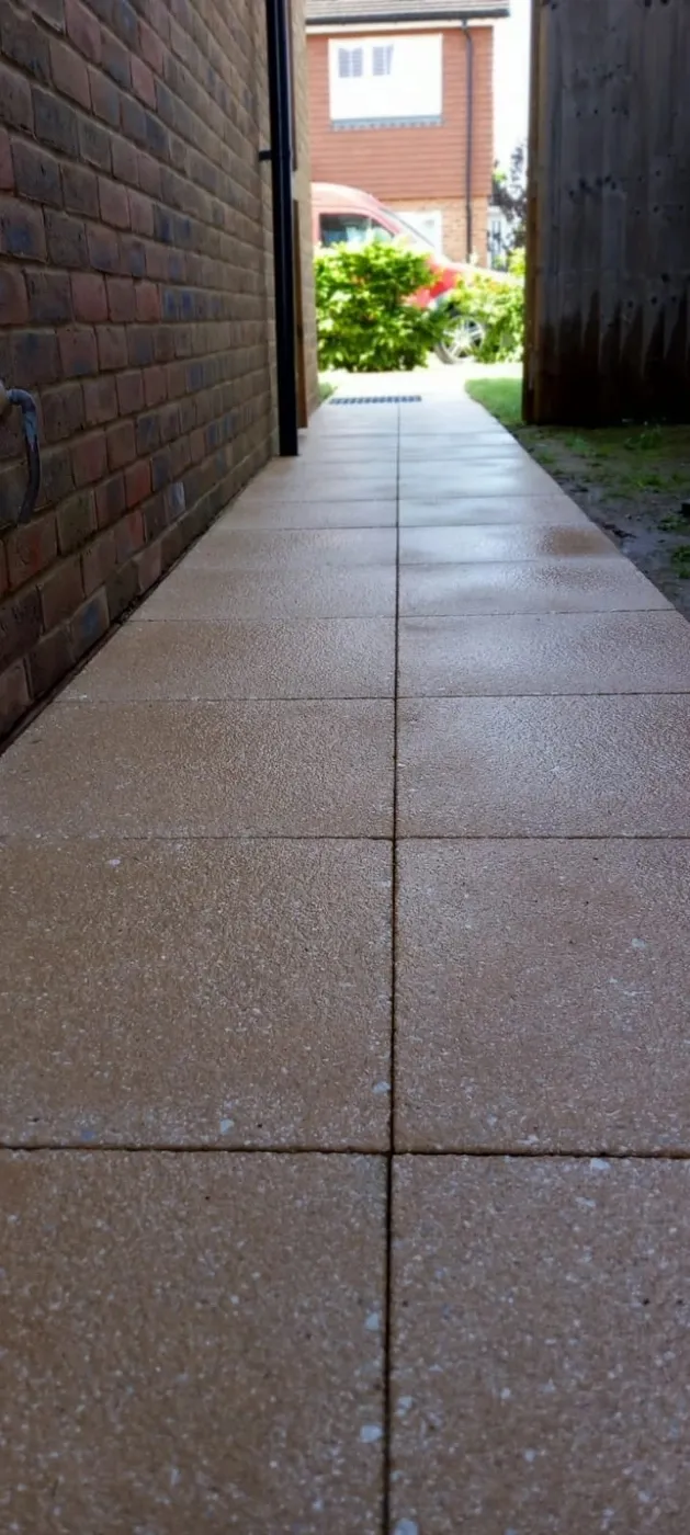 A freshly cleaned slabbed pathway between a brick wall and fence